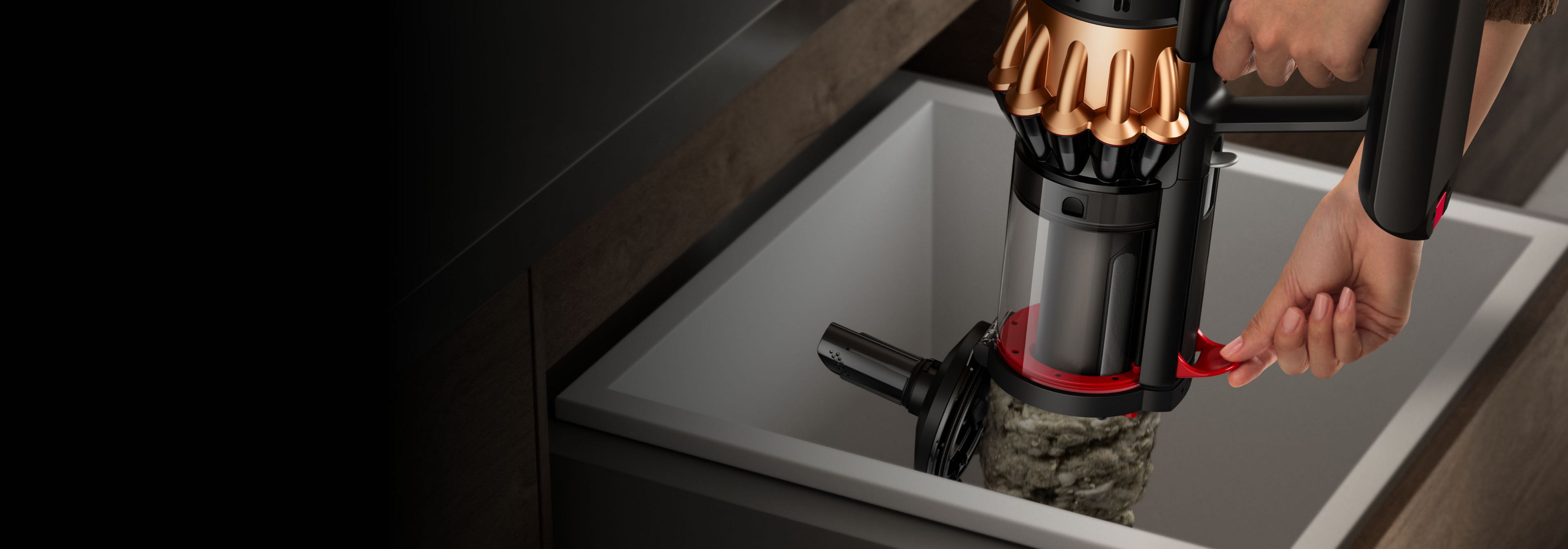 Человек очищает и опорожняет контейнер пылесоса Dyson V16 Piston Animal с помощью бокового рычага.